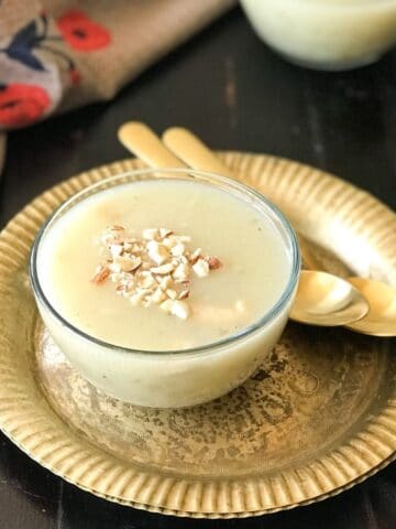 A glass bowl is filled with sabudana kheer and its on the copper plate