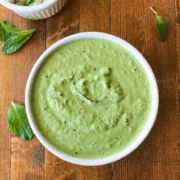 A bowl of food sitting on top of a wooden table, with Chutney and Mint