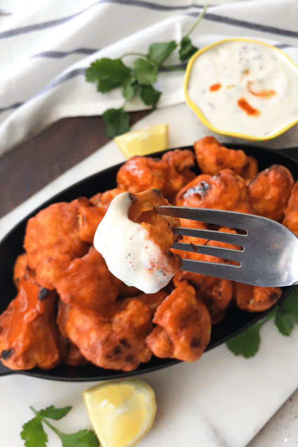 A plate of food with a fork, with Cauliflower and Buffalo wing