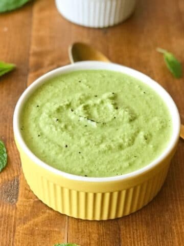 A yellow bowl is filled with pudina chutney and is on the table