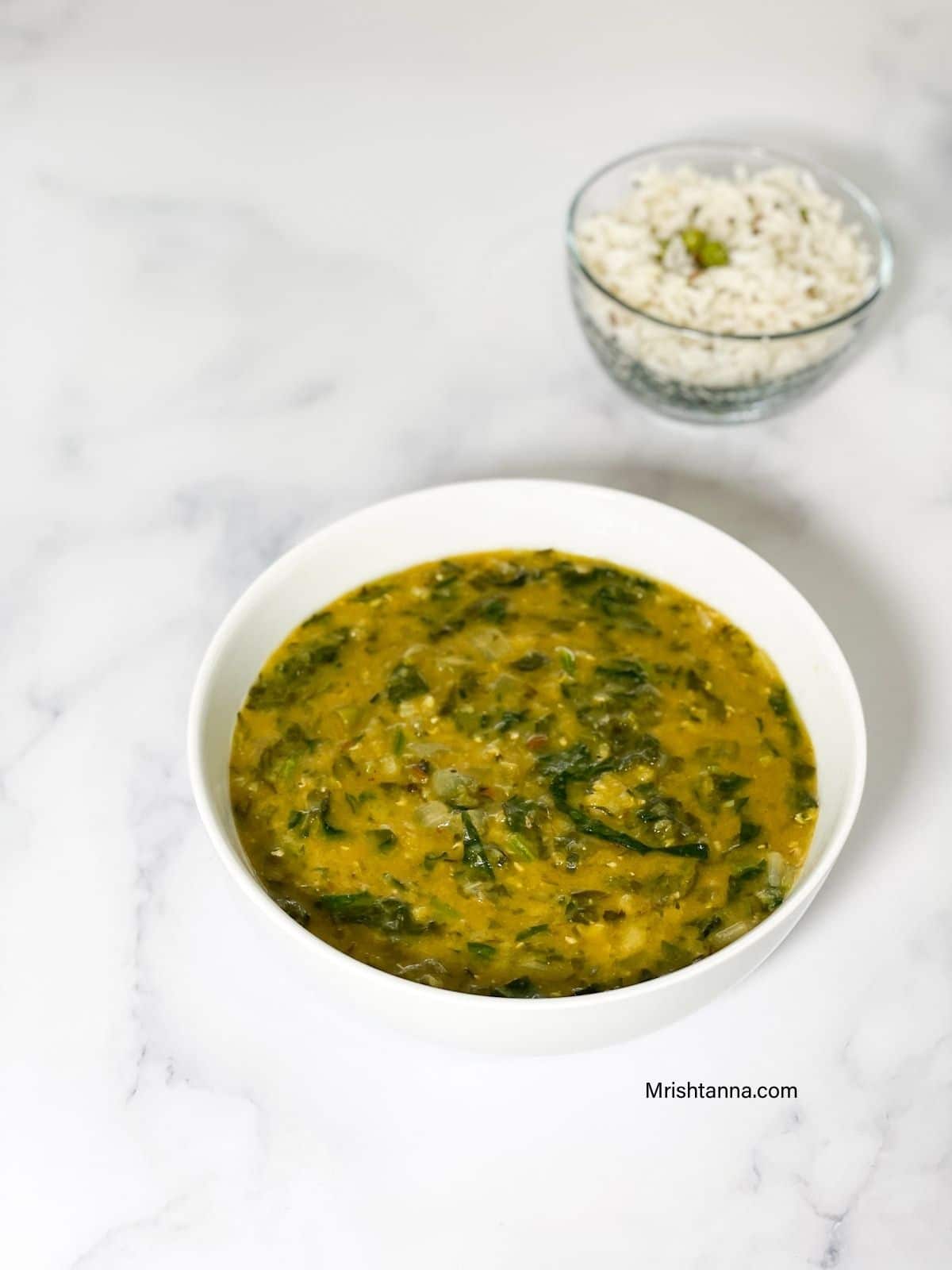 A white bowl spinach dal is on the table.
