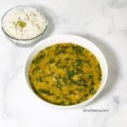 A bowl of palak dal is on the white table