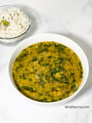 A bowl of palak dal is on the white table