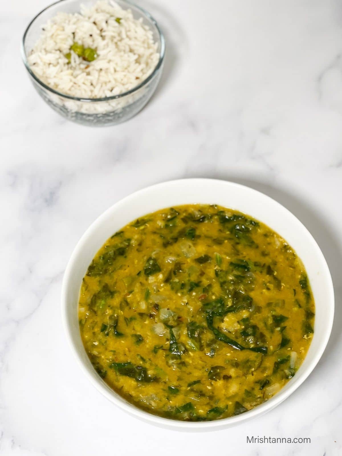 A white of bowl is with dal palak on the table