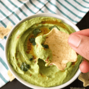 A person holding chips with hummus