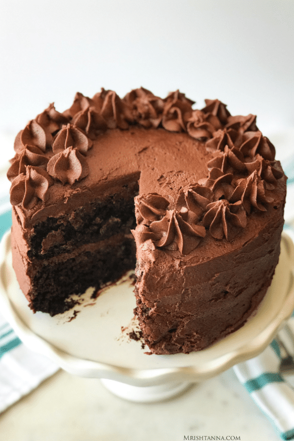 A close up of a piece of chocolate cake on a plate, with frosting