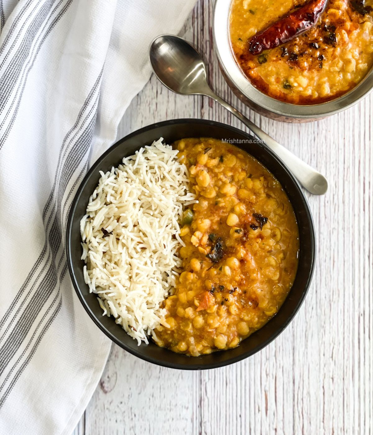 A bowl is with jeera rice and chana dal on the table.