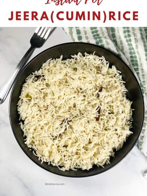A plate of cumin rice is on the marble table with fork by the side.