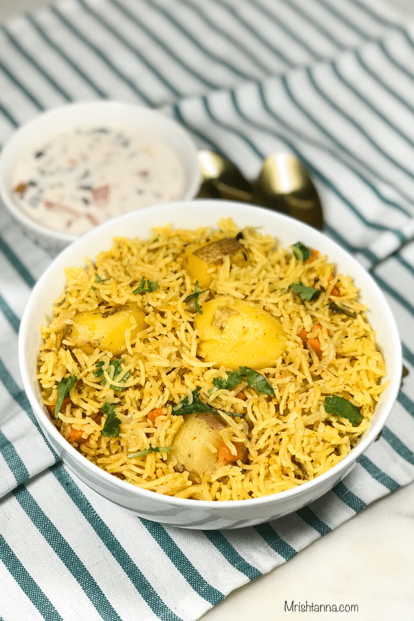 A bowl of food on a plate, with Biryani and Rice