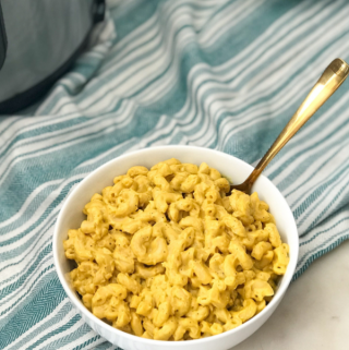 A bowl of mac and cheese with a golden spoon inserted