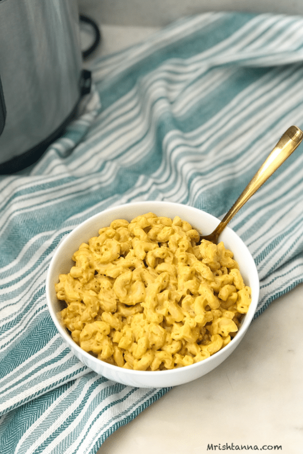 A bowl of mac and cheese with a golden spoon inserted