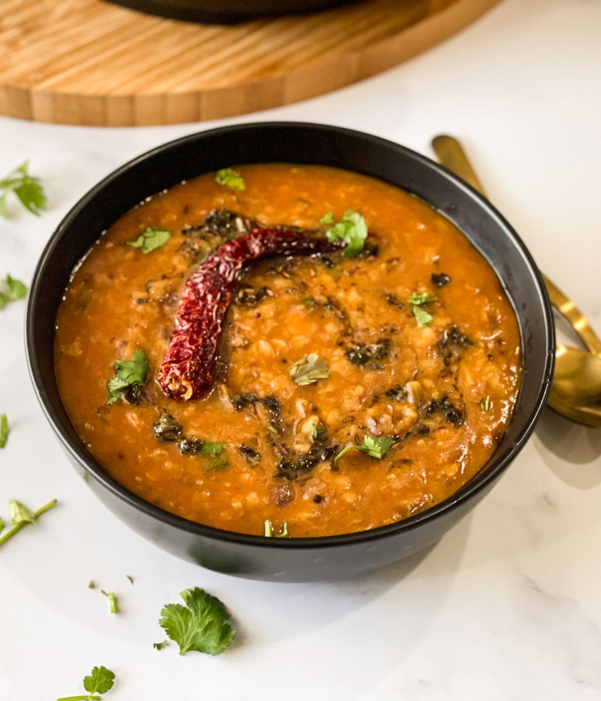 A black color bowl is filled with dal tadka
