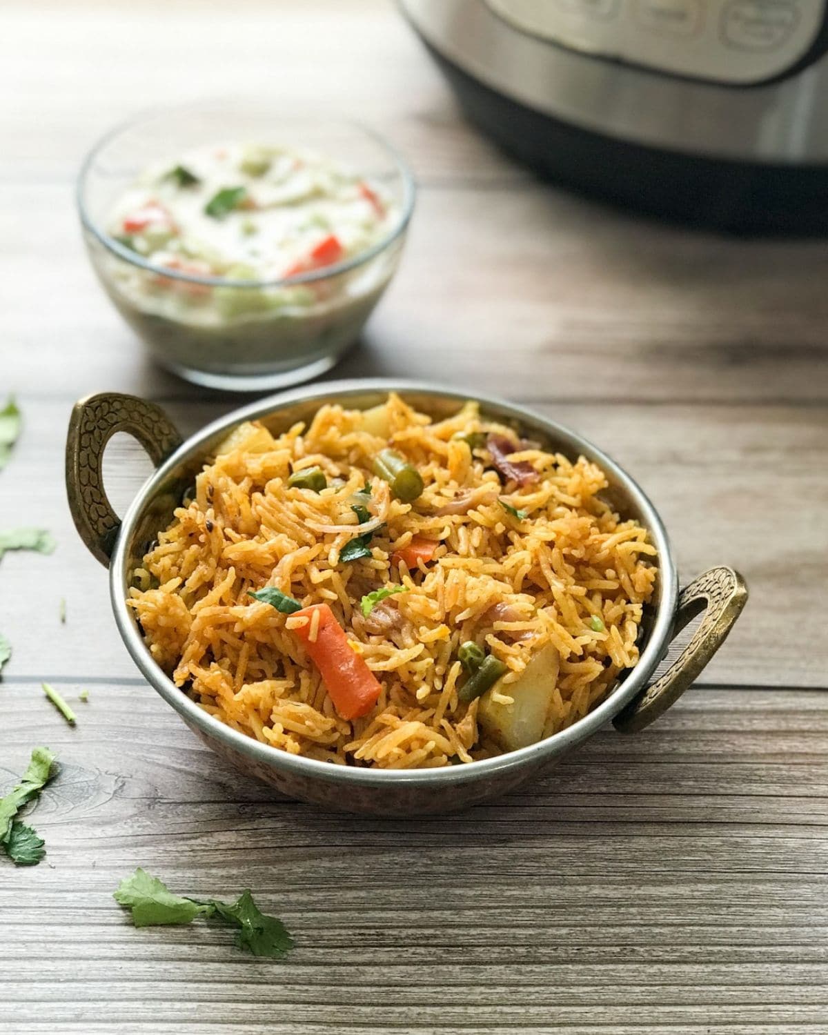 A copper bowl is with vegetable biryani over the table