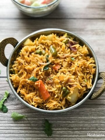 A bowl of veg biryani is on the wooden table