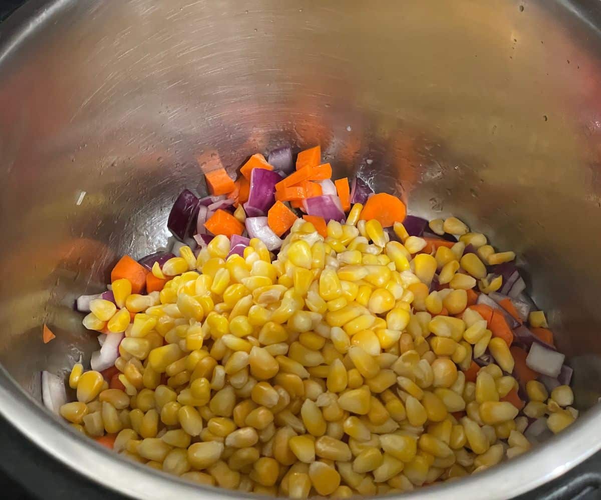 An instant pot is with corns, and carrots.