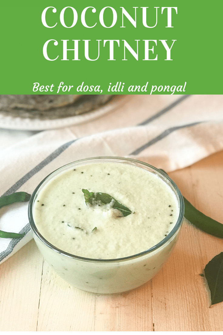 A bowl of coconut chutney sitting on top of a wooden table and curry leaves for garnish
