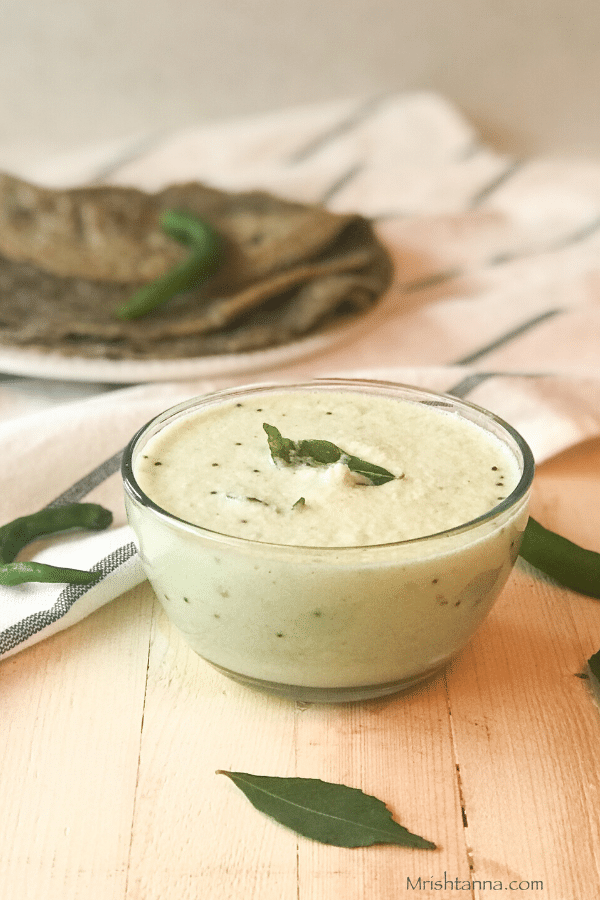 A bowl of soup sitting on top of a wooden table, with Coconut chutney