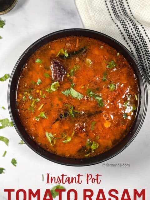 A bowl of Tomato rasam is on the table.