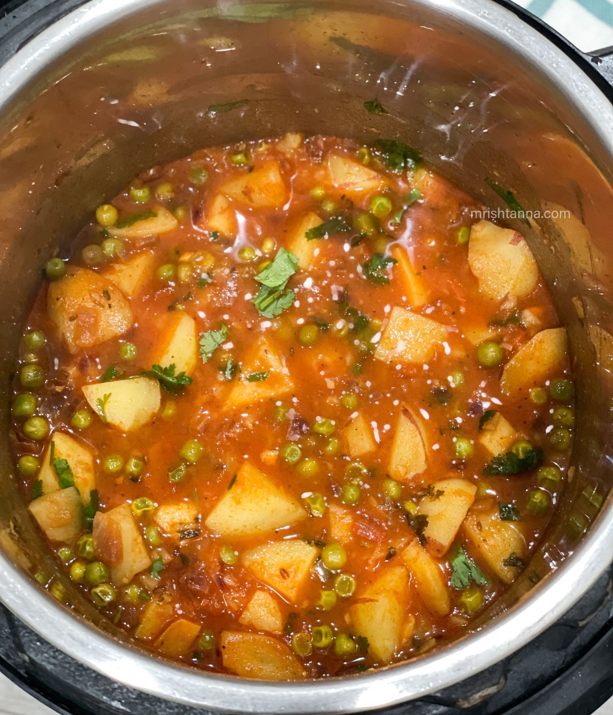 An Instant pot is full of aloo matar curry.