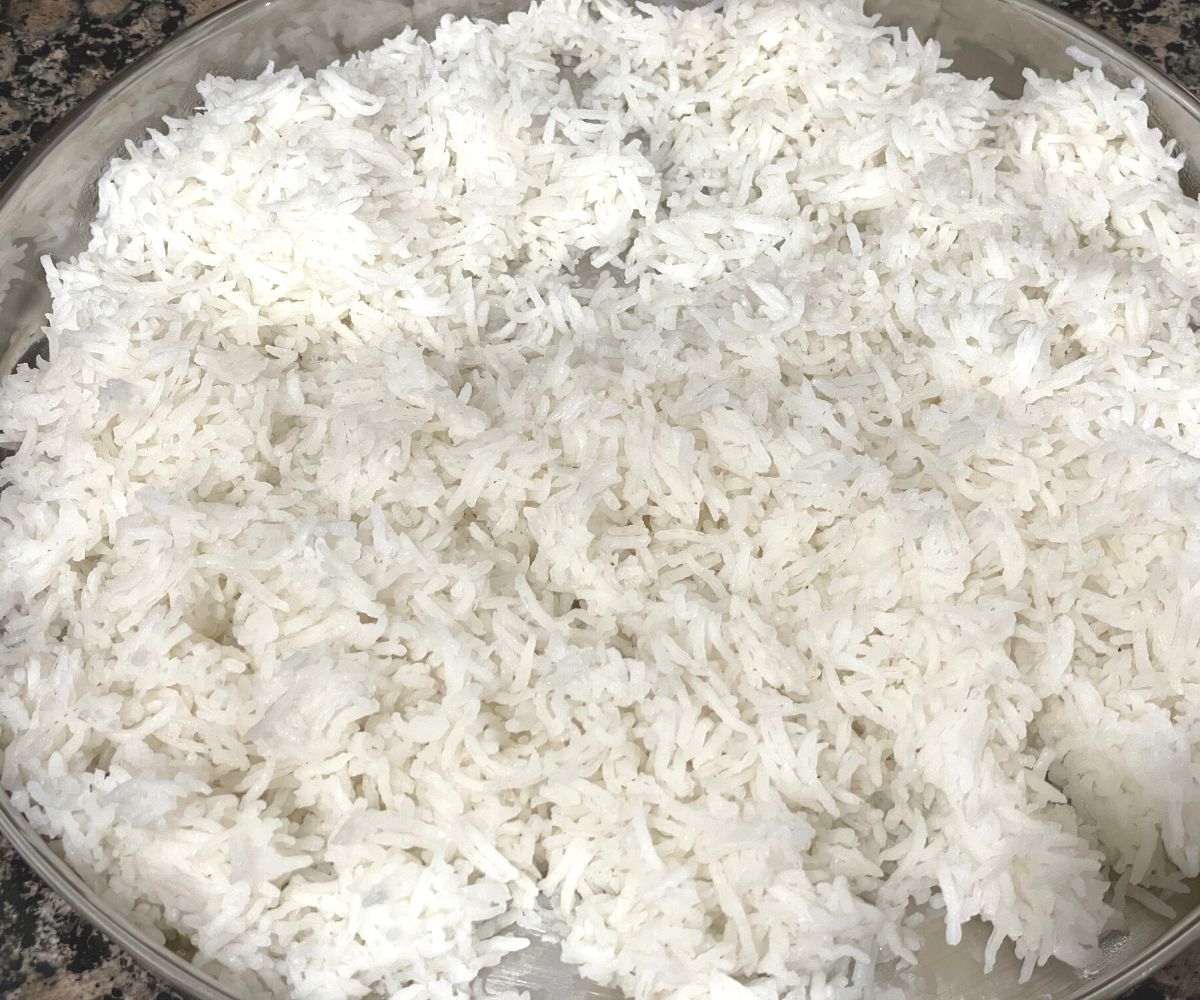 A large plate is filled with cooked basmati rice.