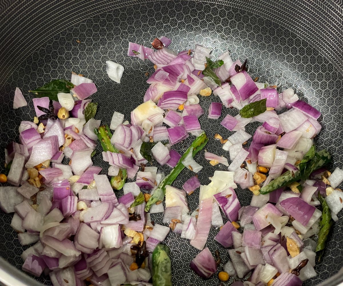 A pan is with onions, garlic, ginger and chilies over the heat.