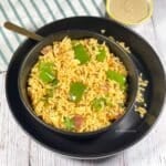 A bowl of capsicum masala rice on the plate along with a bowl of chutney.