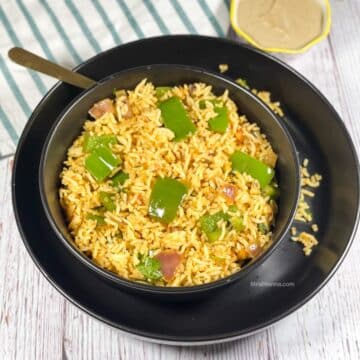 A bowl of capsicum masala rice on the plate along with a bowl of chutney.