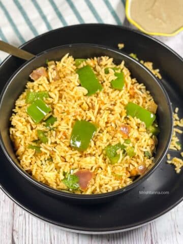 A bowl of capsicum masala rice on the plate along with a bowl of chutney.