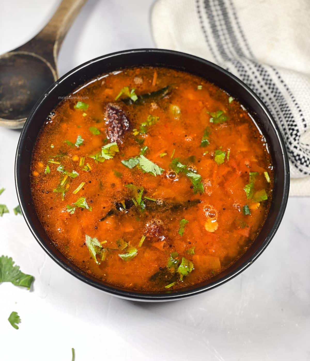 A bowl has Instant pot rasam and topped with cilantro.