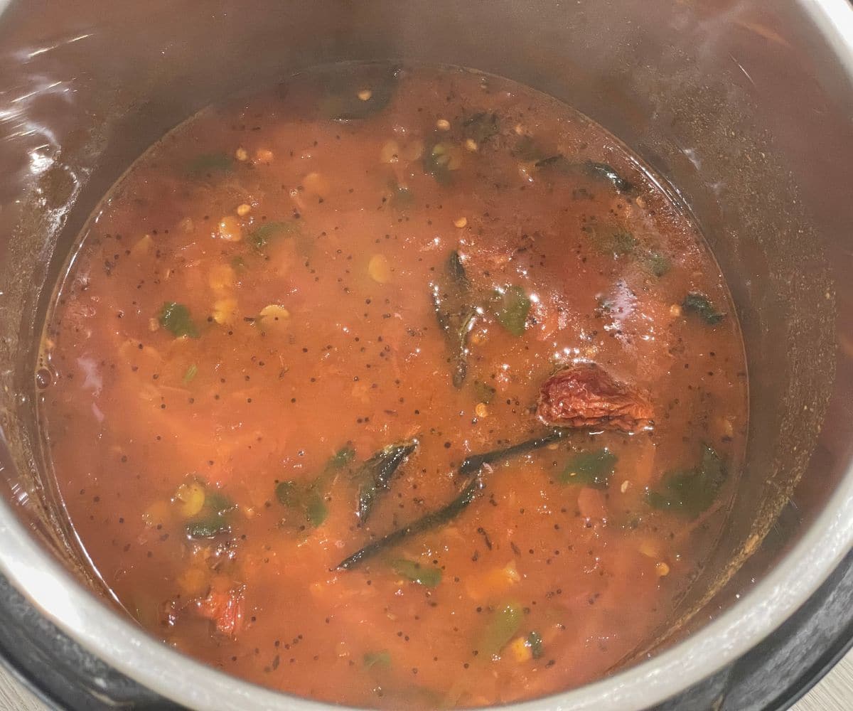 An instant pot is full of tomato rasam.