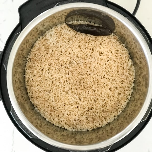 An instant pot filled with rice and a bay leaf