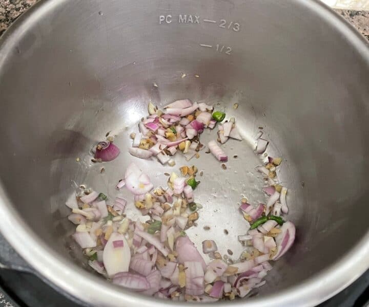 An instant pot is on cooking mode with chopped onions