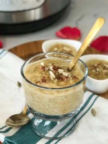A glass bowl is with semiya kheer and topped with nuts.
