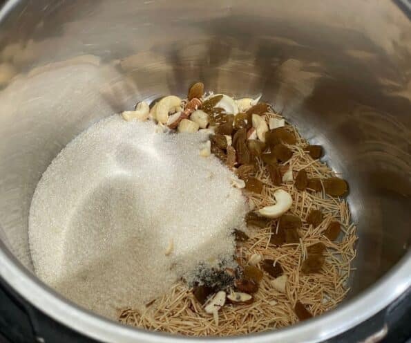 An instant pot is with vermicelli strands, sugar and dry fruits.