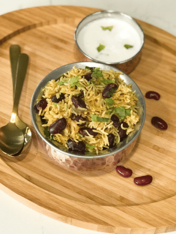 A plate of food on a wooden table, with Rice and Kidney bean