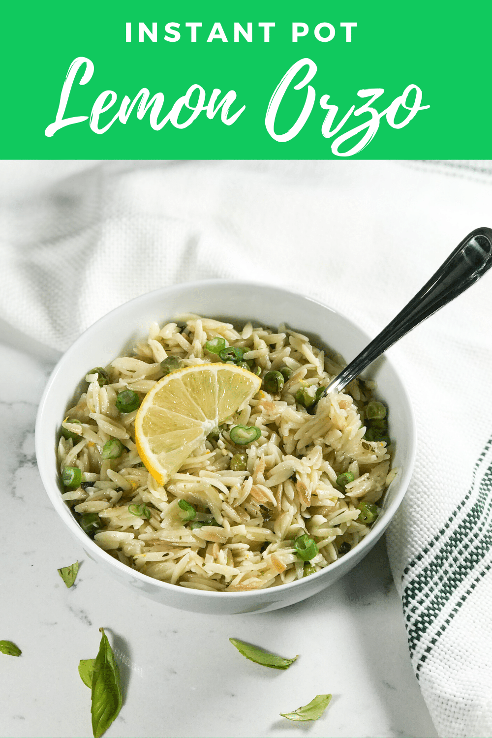 A white bowl filled, with Orzo and lemon wedge for garnish