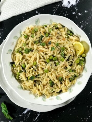 A plate of lemon orzo is on the table with lemon