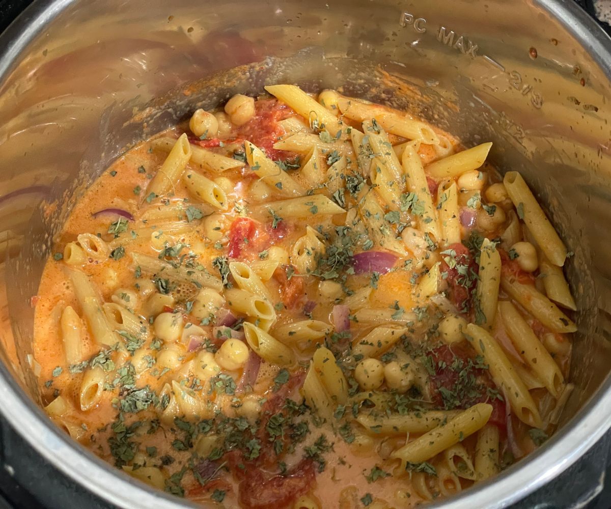 An instant pot is filled with pasta and tikka masala spices.