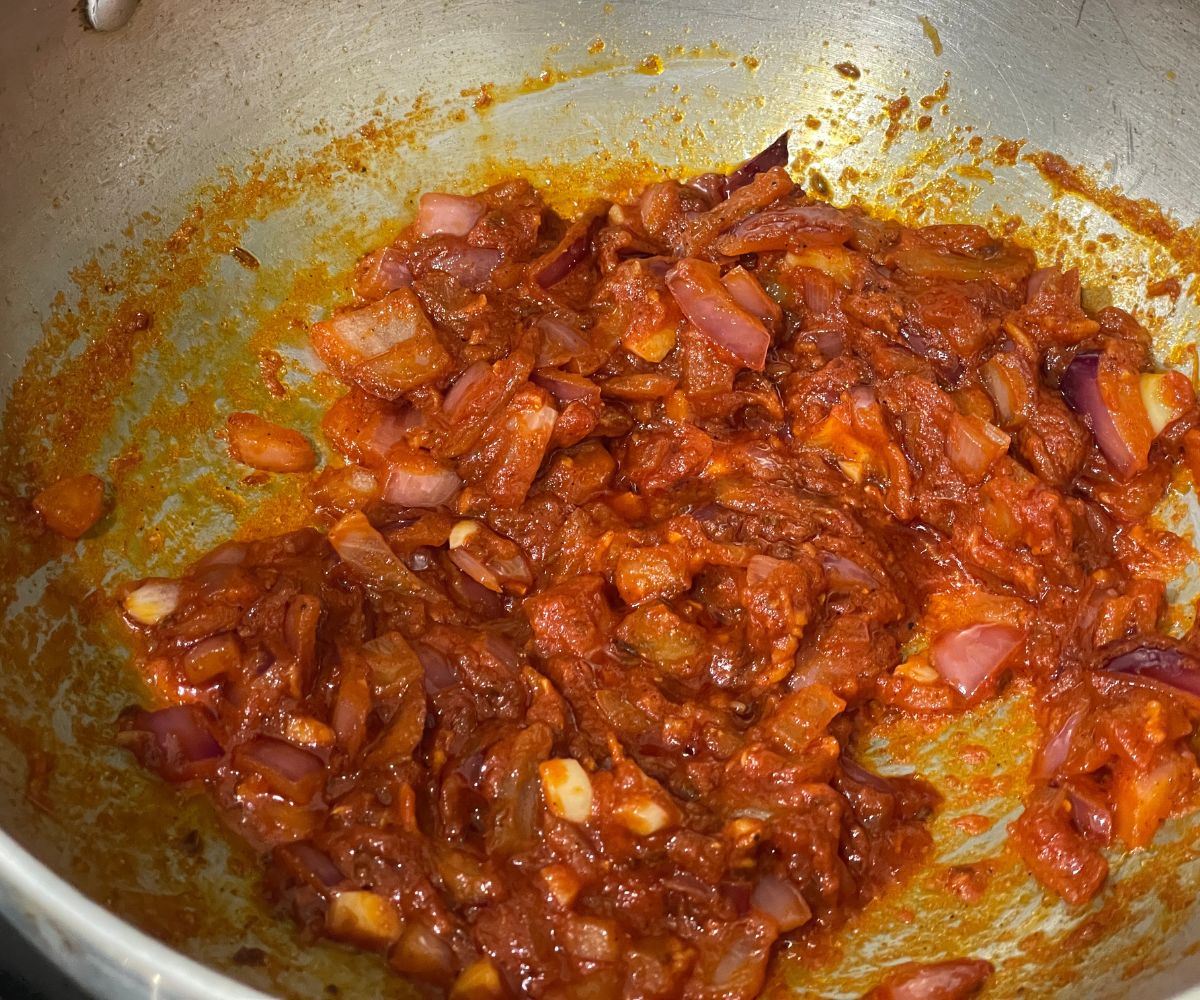 A pan is with spices and tomato paste for rajma curry.