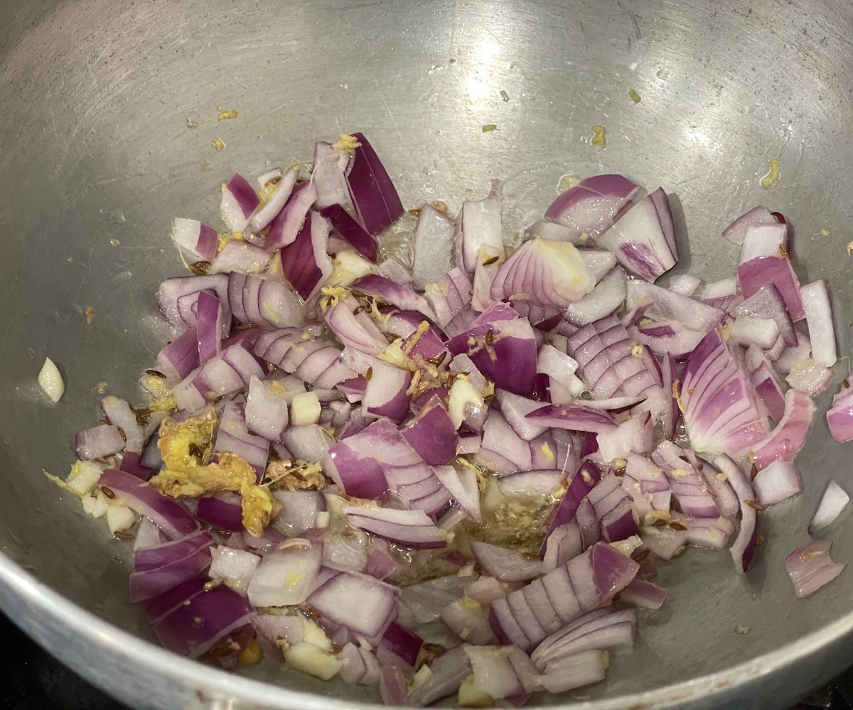 A pan is with onions and garlic over the heat.