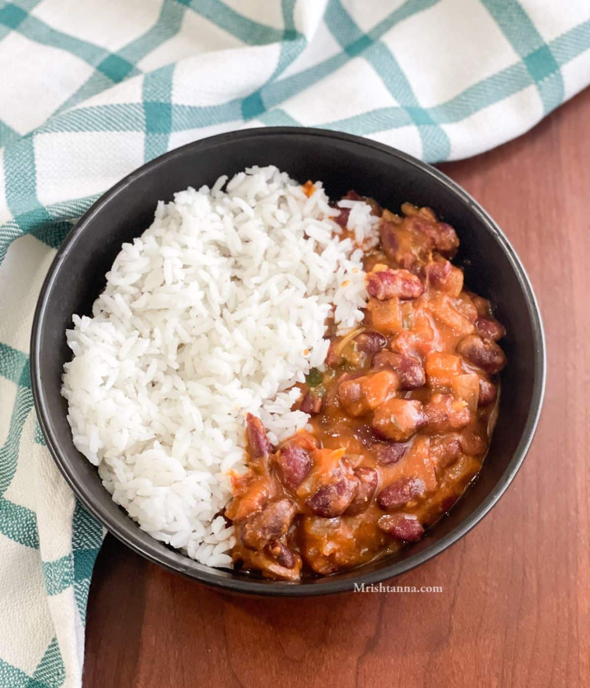 A bowl is with rajma curry and rice on the table.