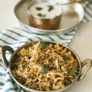 A bowl of rice on a plate, with curd