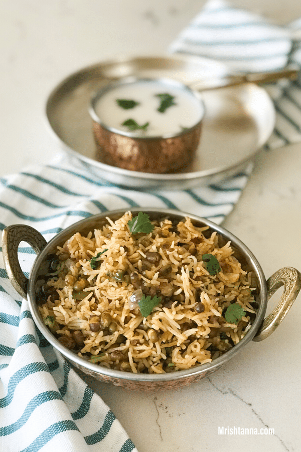 A bowl of rice on the table , with curd by the side 