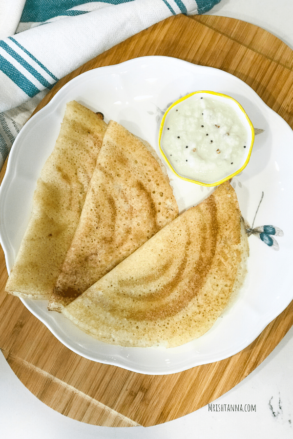 three dosas on a plate along with chutney