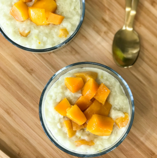 A bowl of food on a plate on a wooden table, with Mango and Rice