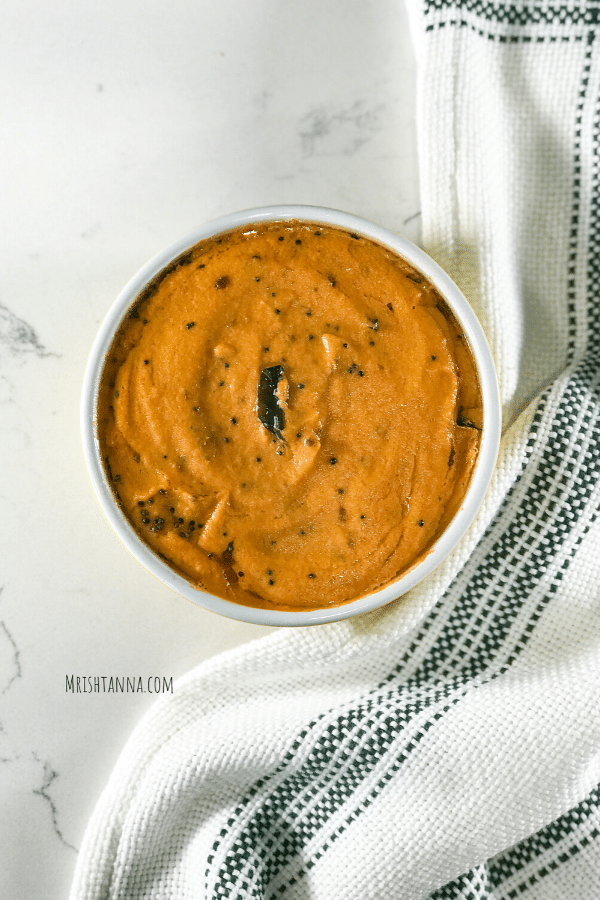 A bowl of food sitting on a table, with Chutney and Tomato