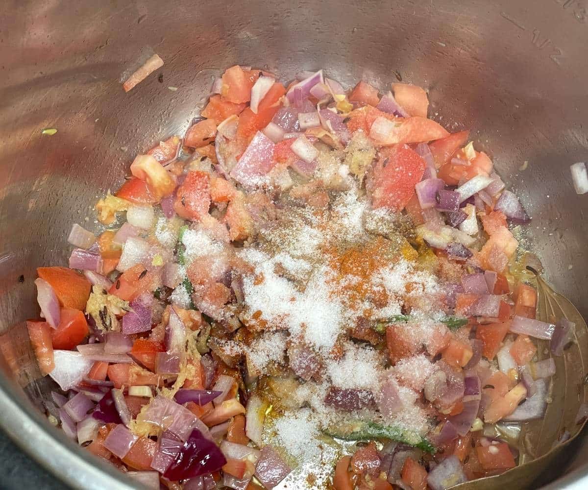 A pot has tomatoes spices for green gram pulao.