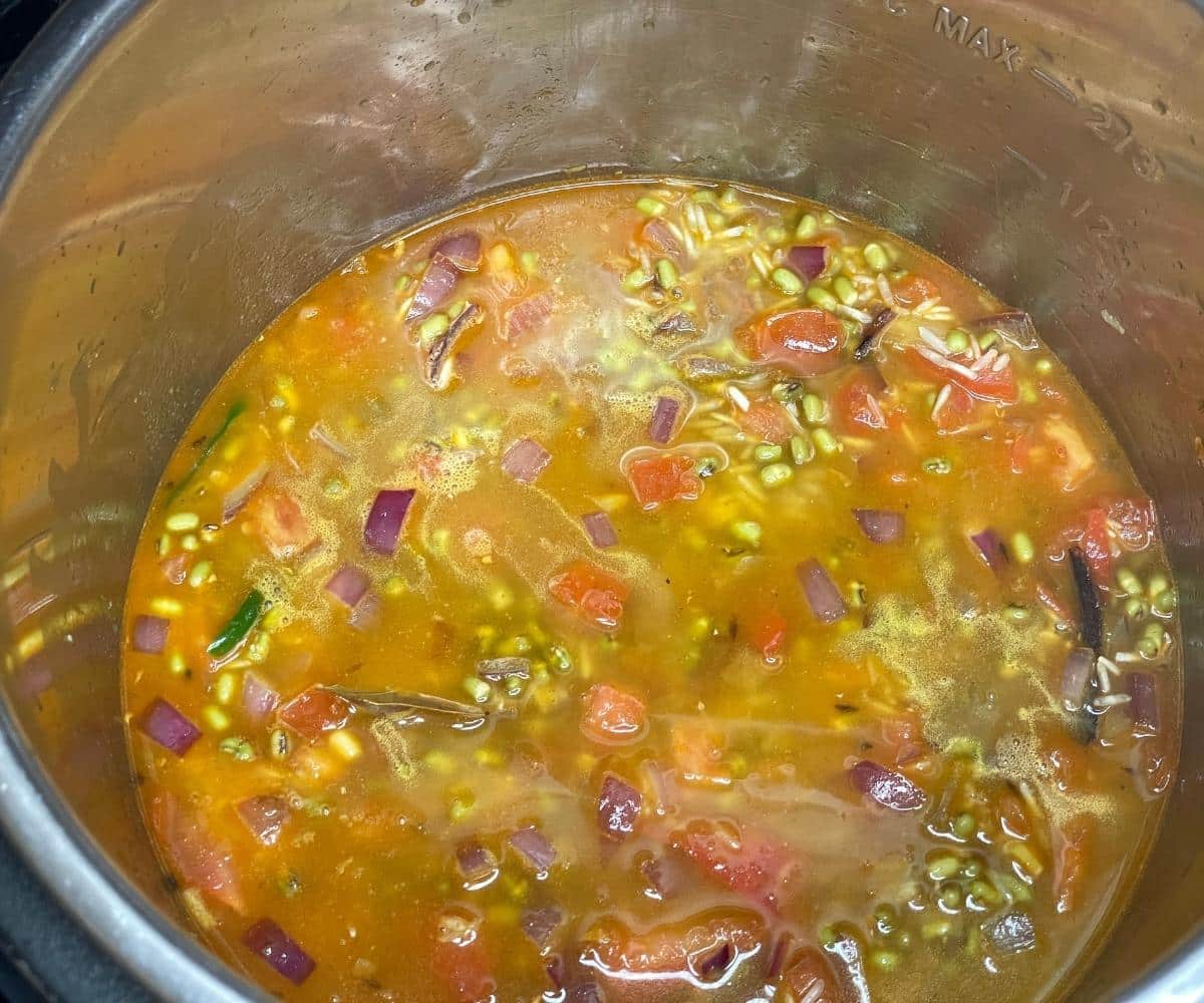 An instant pot is with all the ingredients for green gram pulao.