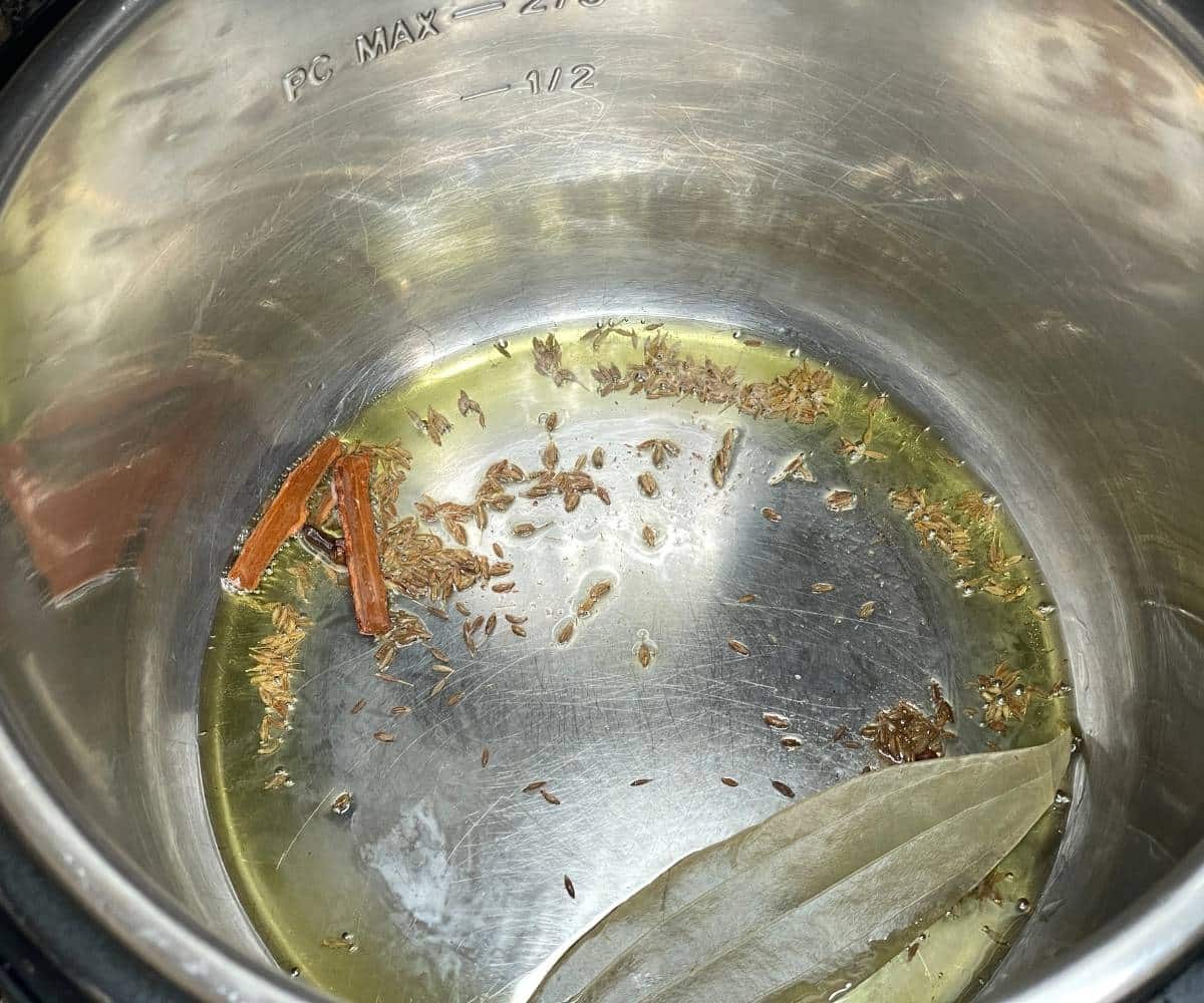 An instant pot has oil, bay leaf for green gram pulao recipe.