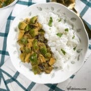 A plate is with potato capsicum curry and white rice.